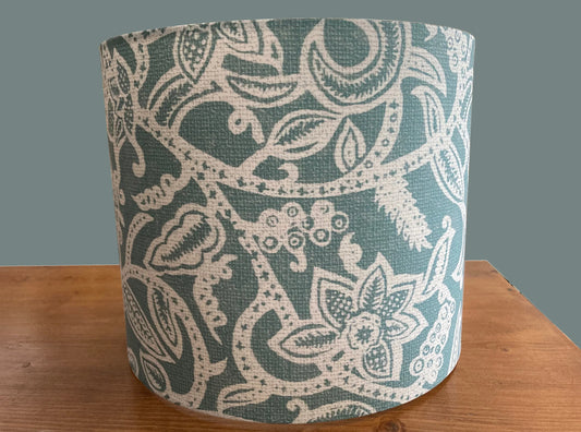 Teal and cream floral patterned drum lampshade on wooden surface