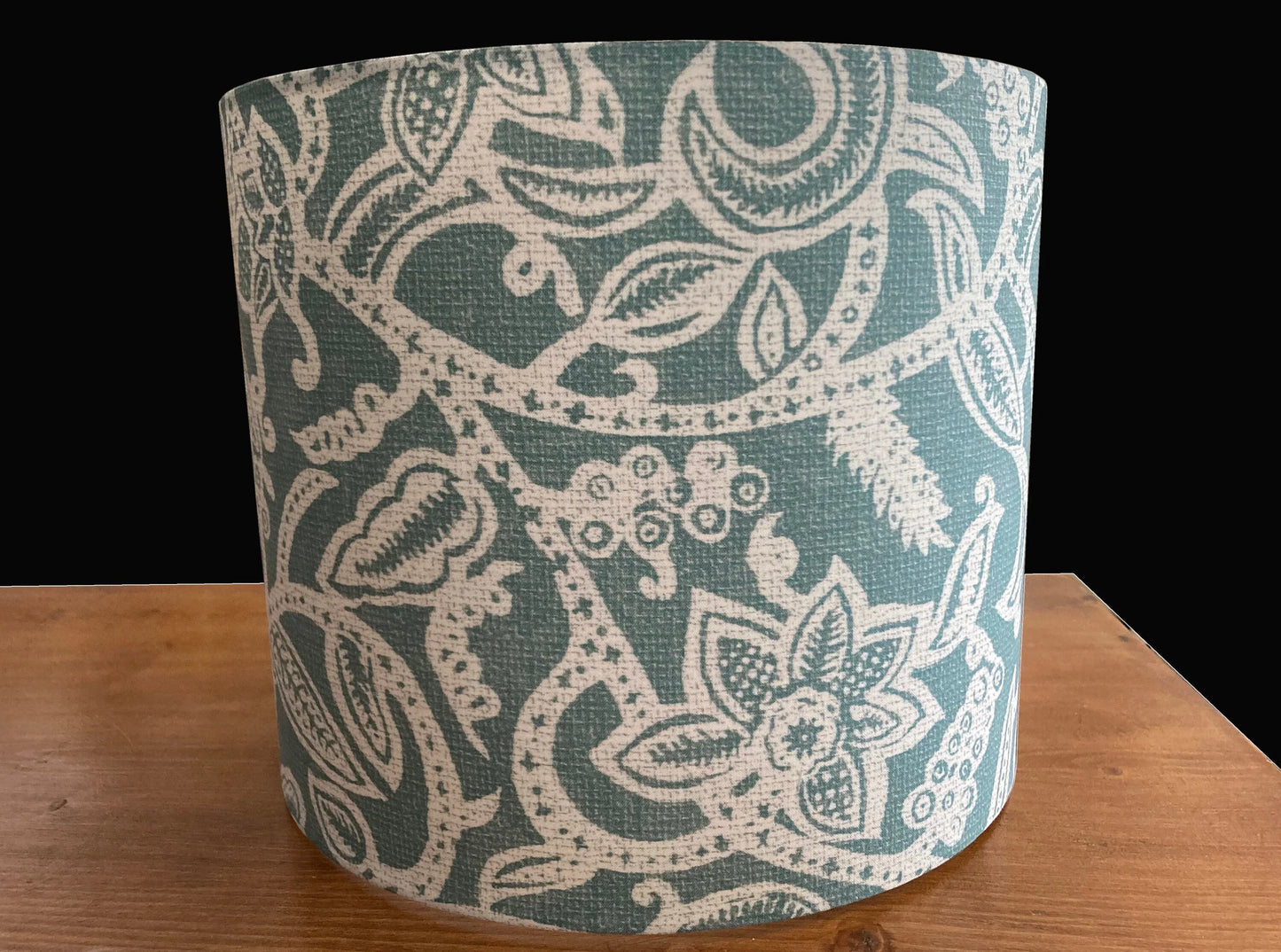 Teal and cream floral patterned lampshade on wooden surface, decorative lighting accessory