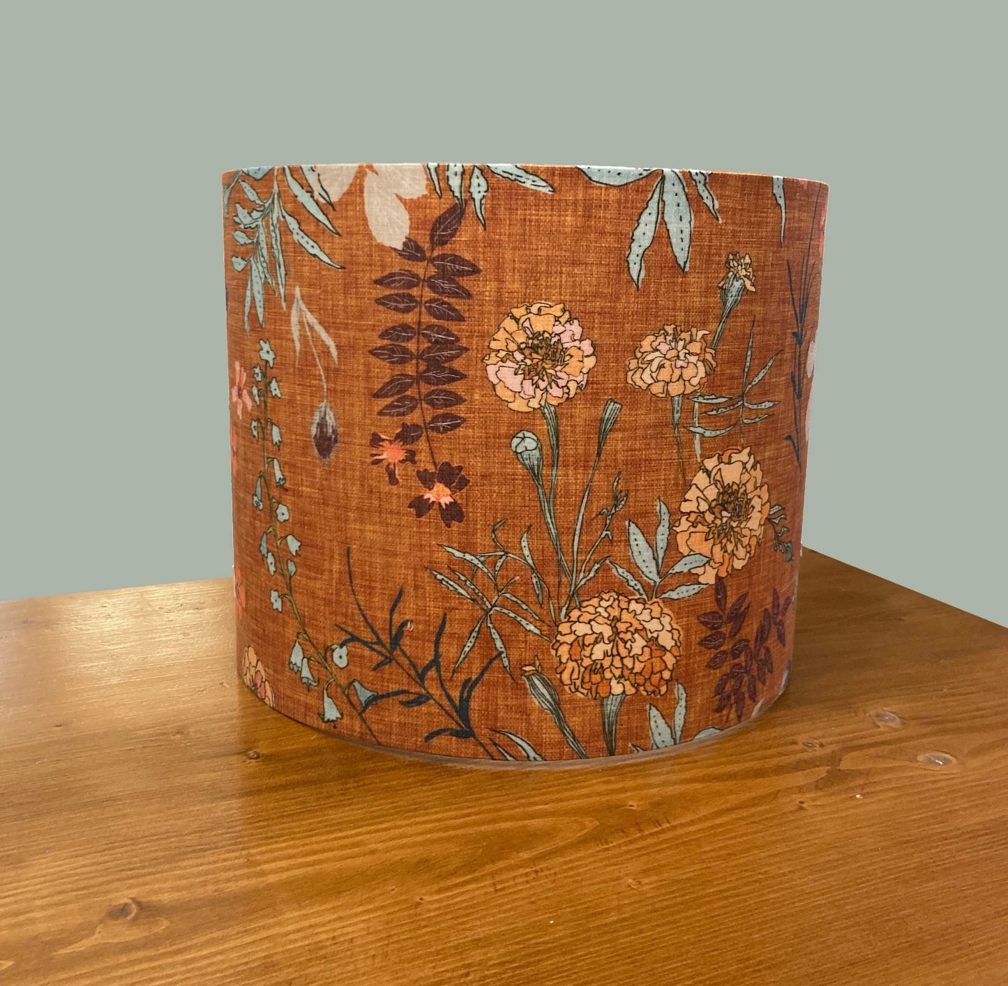 Rustic floral lampshade with marigold print on warm orange fabric, perfect for cozy home decor