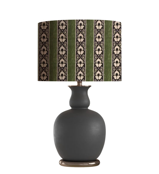 Green and cream patterned lampshade on a dark gray ceramic table lamp base